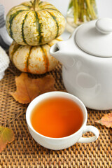 Tea pot, cup of hot beverage and autumn leaves on table