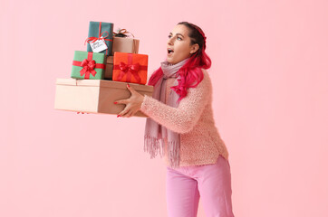 Beautiful woman with Christmas gifts on pink background