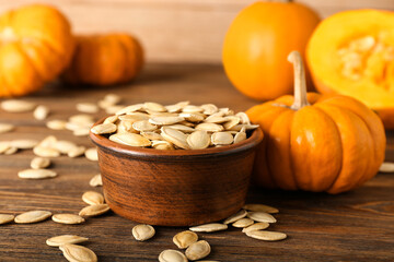 Bowl with natural pumpkin seeds on wooden background