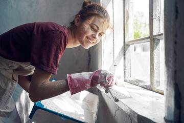 woman with brush paints window sill at home near window interior renovation