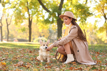 Stylish young woman with cute Corgi dog in autumn park