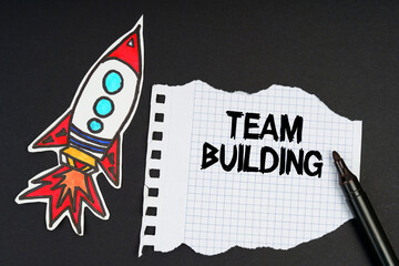 On a black background, a rocket, a marker and paper with the inscription - TEAM BUILDING