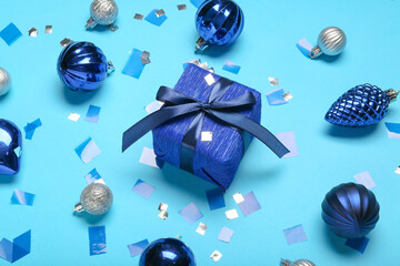 Composition with Christmas gift box and balls on blue background
