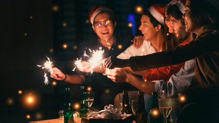 Happy multiracial people in party holding sparklers and champagne glasses celebrating New year eve together, excited diverse young friends having fun enjoying celebration together.