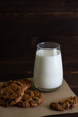 Delicious chocolate cookies, pieces of dark chocolate and a glass of milk on a textured background. Close-up.