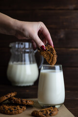 A woman's hand dips cookies in milk. Organic breakfast of pastries. Milk and cookies.