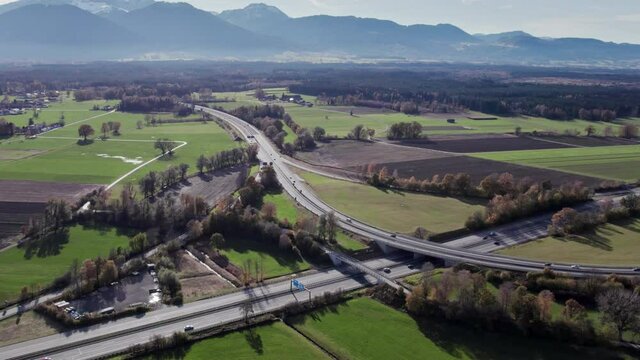 Aerial Drone Shot of a Highway in southern Germany flying towards a interchange section of the motorway showing the smooth flowing traffic on it with a lot of different cars.