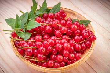 Table top view bunch of red currant in basket, Red currant berries with leaf on wooden table.