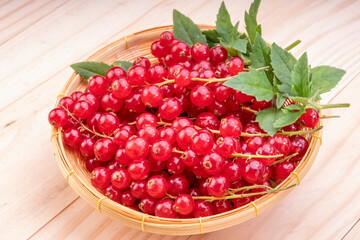 Table top view bunch of red currant in basket, Red currant berries with leaf on wooden table.