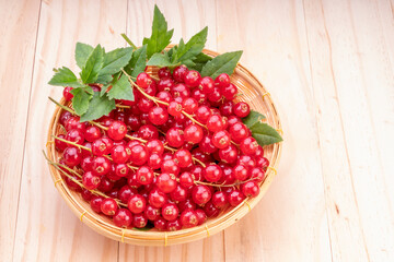 Table top view bunch of red currant in basket, Red currant berries with leaf on wooden table.