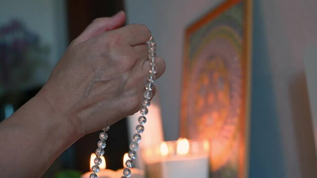 close-up of hands fingering rosary against the background of burning candles isoteric theme. High quality 4k footage