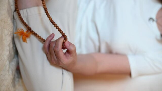 vertical video. a man sits in a lotus position. close-up of hands fingering rosary. isoteric theme. High quality 4k footage