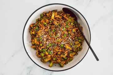 vegan teriyaki stir fry with broccoli peas and shredded tofu topped with sesame seeds, healthy plant-based food