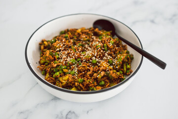 vegan teriyaki stir fry with broccoli peas and shredded tofu topped with sesame seeds, healthy plant-based food