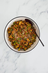 vegan teriyaki stir fry with broccoli peas and shredded tofu topped with sesame seeds, healthy plant-based food