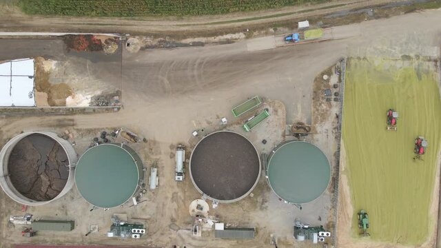 Aerial top down of a biogas farm renewable green energy production from raw agricultural waste in to methane and carbon dioxide, tractor and excavator working on site