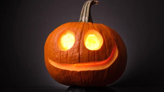 A Glowing Pumpkin With A Nice Smile Spinning in The Dark, Jack O Lanterns. - Close up 