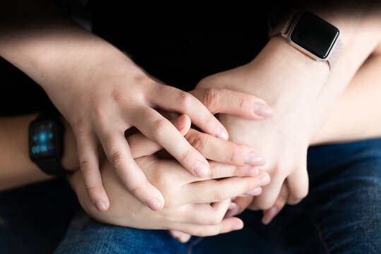 The hands of the mother and children on a dark background are intertwined. Family insurance concept. Photo in front.