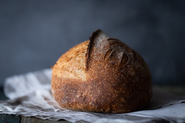 Homemade wheat whole grain sourdough bread on a dark background and a wooden table. Photo in front.