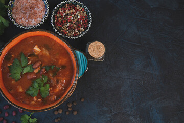 Red bean soup with herbs and spices on a dark table background. Top view with copy space.