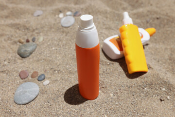 Sunscreens in colourful unbranded bottles on sand