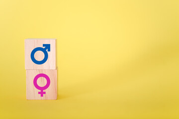 Male and female icon symbols on wooden blocks against yellow background.