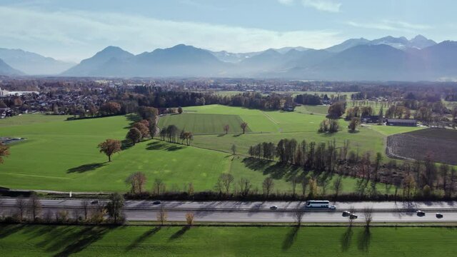 Aerial Drone shot of a highway in southern Germany flying from right to left following a Bus on the lane with a nice view over the scenery and the beautiful Mountains in the Background.
