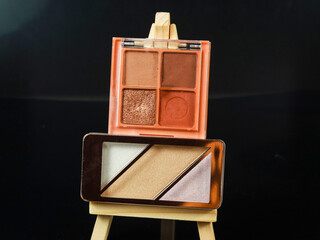 highlighter, blusher pallet on wooden frame with black background