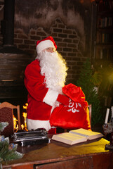 Obraz na płótnie Canvas Santa Claus for the New Year 2022 and Christmas with a large bag of gifts in a red suit