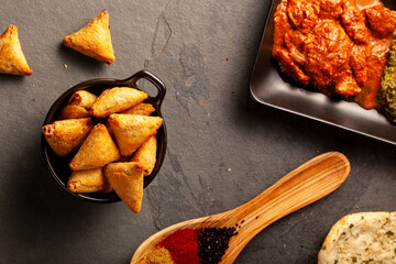 Close up image of a table with delicious dishes from India. Low light dark background with naan,...