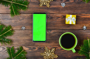Fototapeta na wymiar green screen technology cell phone on christmas decoration table top view flat lay, mock up for copy space text, smart phone chroma key, new year online concept no people
