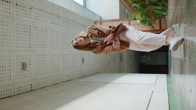 Young woman, talented student, is having fun in hallway, recording vertical video, switches on camera to film herself dancing and jumping, social media concept, Slow motion.