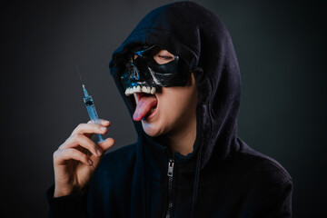 Drug addiction concept. Fear of vaccinations and injections. A person in a sweatshirt with a hood...