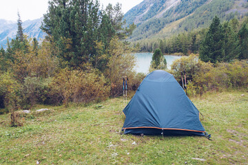 Camping tent in forest on the mountain river bank. Tourism concept, outdoors leisure. Life in a tent. Altai Mountains, Russia. Kucherla lake.