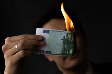 businessman holding burning euro money