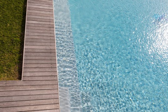 Aerial view of a swimming pool with a decking edge and plants in a garden.