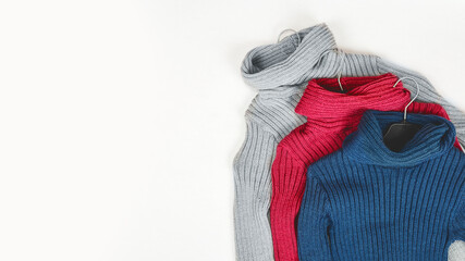 color and gray winter sweaters on hangers trendy fashion autumn warm. top view. copy space