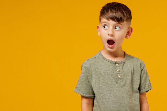 Little small smiling happy boy 6-7 years old wearing green casual t-shirt look aside with open mouth isolated on plain yellow background studio portrait. Mother's Day love family lifestyle concept