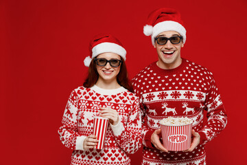 Young fun couple friends man woman in 3d glasses watch movie film hold bucket of popcorn cup of...