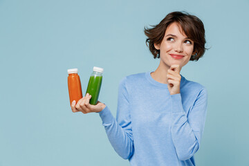 Young minded woman wear casual sweater hold pressed juice green orange vegetable smoothie as detox...