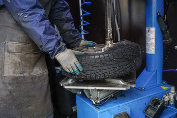 The process of replacing the removing the wheel disk of the car on the mobile tire fitting. the moment of separation of the tire from the disk on the equipment. Men's hands of a worker in the frame.