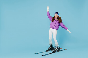 Full body skier beginner fun cool woman wearing warm purple padded windbreaker jacket ski goggles mask spend extreme weekend in mountains skiing leaning back isolated on plain blue background studio