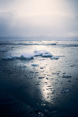 Winter landscape of the Avacha bay. Snowy mountains and ocean with ice floes at snowy weather. Kamchatka peninsula, Russia