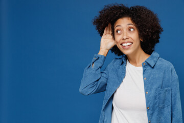 Young curious smiling happy black woman in casual clothes shirt white t-shirt try hear you overhear...