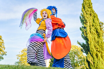 Positive clowns standing back to back during masquerade in park