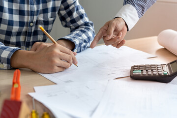 The head of the construction team and the owner of the house building company look at the blueprint...