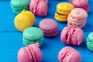 Pile of delicious colorful macarons on blue background