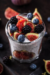 Healthy chia pudding with figs and dark berries in glass on the rustic background. Selective focus. Shallow depth of field.
