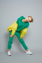 Naklejka premium Fashion model in green sport suit, down jacket, white seakers.
