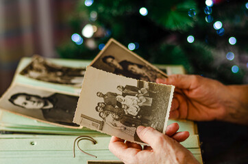 Cherkasy/Ukraine- December 12, 2019: Female hands holding and old photo of her relatives. Vintage photo album with photos. Family and life values concept.